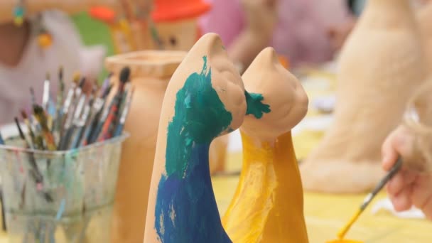 Child painting brushes on the clay figure outdoors — Stock Video