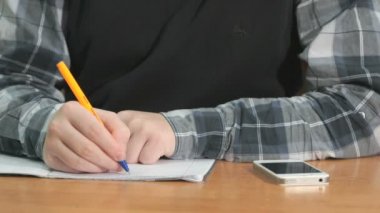 Bilinmeyen bir adam defter kalem kullanarak metni yazar