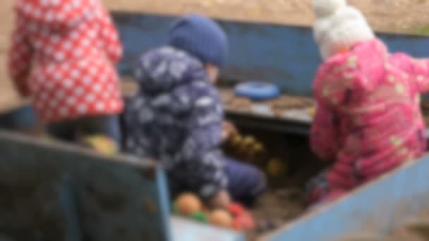 Kleine Kinder spielen mit Sand im Sandkasten — Stockvideo