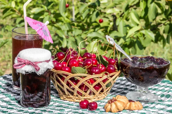 Корзина вишни, вишневое варенье с печеньем, банка вишневого варенья и стакан компота — стоковое фото