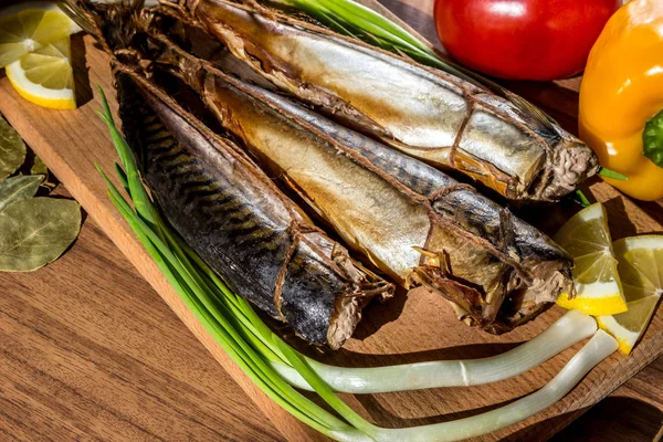 Maquereau de poisson fumé sur planche à découper en bois sur fond de légumes (poivre, tomate, oignons verts ) — Photo