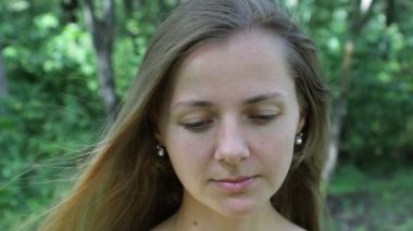 Kadın yukarı bakar ve gülümser, ağır çekimde. Makyaj yok, yüzü çilli.