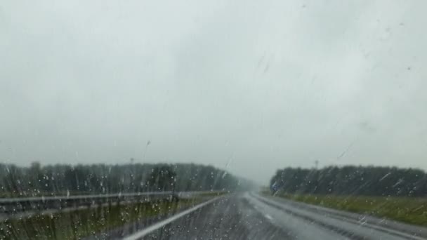 รถกําลังเคลื่อนที่บนถนนในสภาพอากาศที่ฝนตก ฝนตกลงมาที่กระจกหน้ารถ ซึ่งมีนาโนโกโก้ — วีดีโอสต็อก