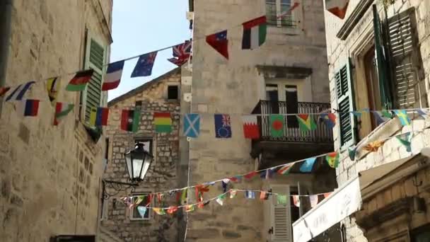 Flaggen verschiedener Länder der Welt wehen. die altstadt kotor in montenegro, platz in der nähe des cafés. 14. September 2019 — Stockvideo