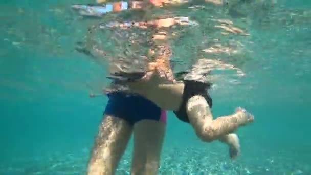Ребенок активно двигает ногами под водой. Один год мальчик плавает в море, мать держит ребенка . — стоковое видео