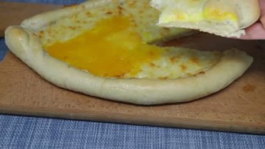 Kadın bir parça khachapuri (peynirli pasta) aldı, ısırdı ve yerine geri koydu..