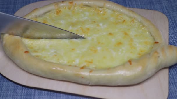 Biten av hemlagad khachapuri (georgiska ost bakverk) skärs med kniv. — Stockvideo