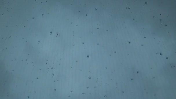 Dešťové kapky dopadají na čelní sklo a stékají po skle jedoucího auta. — Stock video