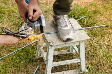 Elektrikli açı öğütücü tutan ve metali kesen adamın elleri, aletten kıvılcımlar.