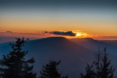 Beautiful sunset with few small clouds and colorful sky from Lysa hora hill in Moravskoslezske Beskydy mountains in Czech republic clipart