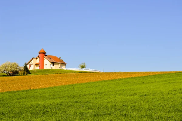 Casa con una torretta su campi coltivati — Foto Stock