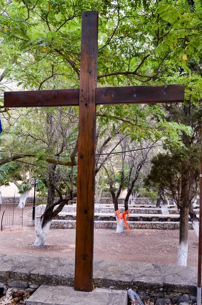 Tmavý dřevěný kříž před sadem — Stock fotografie