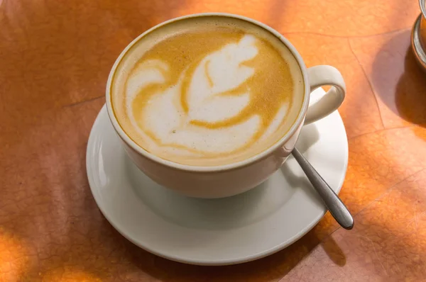 Simple cappuccino on a brown round table in a tropical garden — Stock Photo, Image