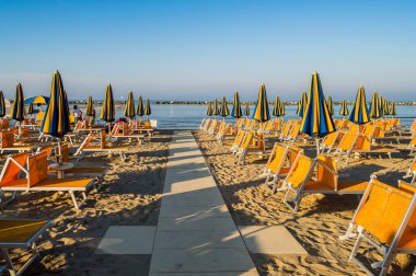 Rimini yakınlarındaki Igea Marina sahilinde turuncu şemsiyeler ve şezlonglar.