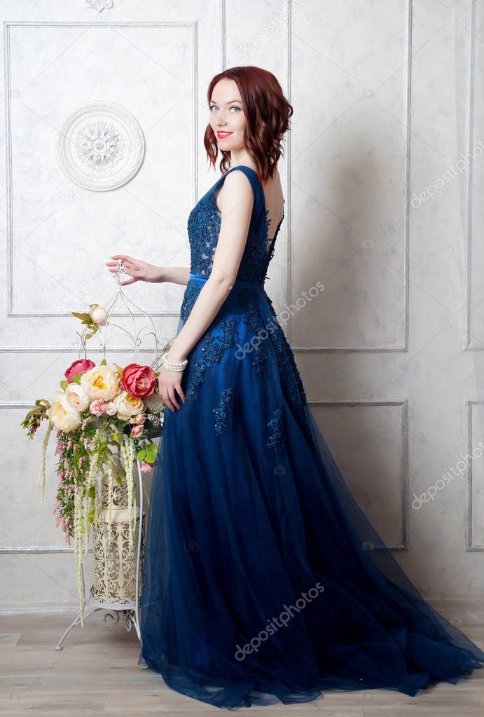 Beautiful young girl in evening dress posing at interior photo s