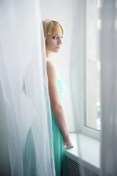 Joven chica solitaria mirando por la ventana — Foto de Stock
