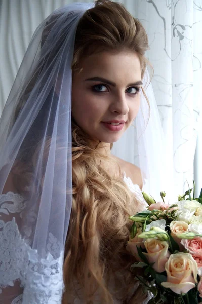 Schöne junge Braut posiert im Hochzeitskleid im Studio — Stockfoto