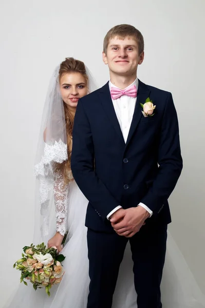 Mooie jonge bruid en bruidegom poseren in studio — Stockfoto