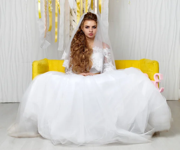 Schöne junge Braut posiert im Hochzeitskleid im Studio — Stockfoto