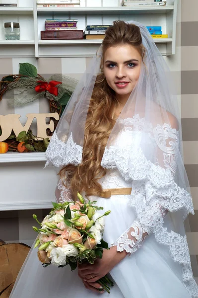 Schöne junge Braut posiert im Hochzeitskleid im Studio — Stockfoto