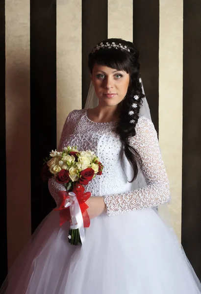 Schöne junge Braut posiert im Hochzeitskleid im Studio — Stockfoto