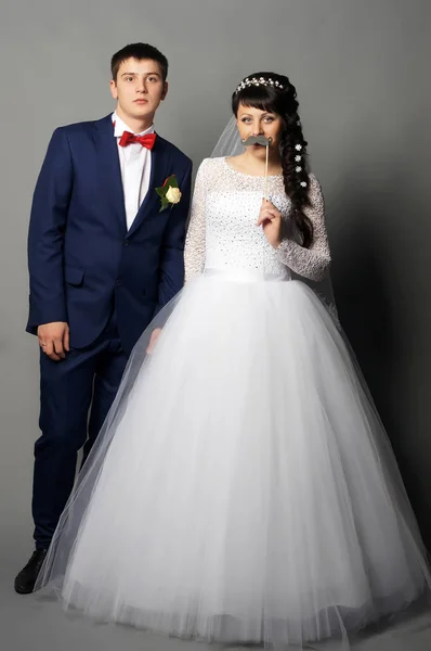 Beautiful young bride and groom posing at studio — Stock Photo, Image