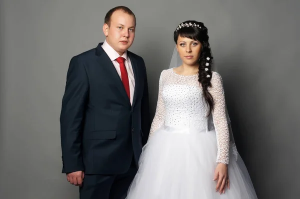 Mooie jonge bruid en bruidegom poseren in studio — Stockfoto