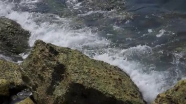 Deniz dalgaları kayalık kıyılara çarpıyor.