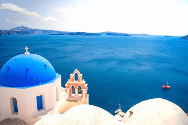 Yunanistan 'ın Santorini adasındaki Oia kasabası. Caldera, Ege denizi üzerinde mavi kubbeleri olan geleneksel ve ünlü evler ve kiliseler