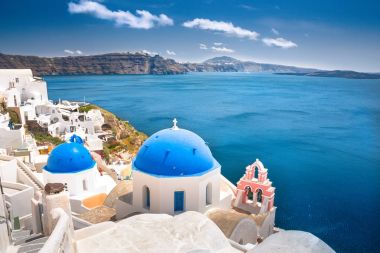 Yunanistan 'ın Santorini adasındaki Oia kasabası. Caldera, Ege denizi üzerinde mavi kubbeleri olan geleneksel ve ünlü evler ve kiliseler