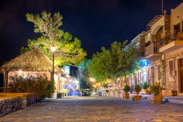 Natt syn på en gata med nattliv, café och restauranger i byn Plaka, vid det gulf of Elounda, nära den berömda ön Spinalonga, Kreta, Grekland 23 September 2017. — Stockfoto