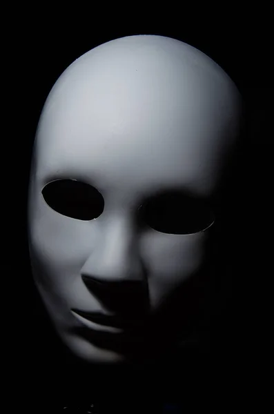 Weiße Maske mit neutralem Ausdruck und Schatten auf dunklem Hintergrund. — Stockfoto