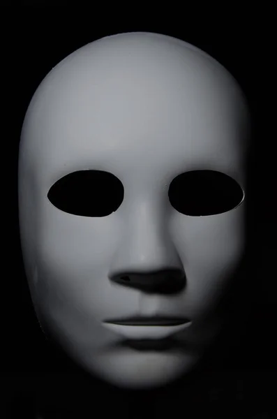 White mask with neutral expression and shadows on dark background. — Stock Photo, Image