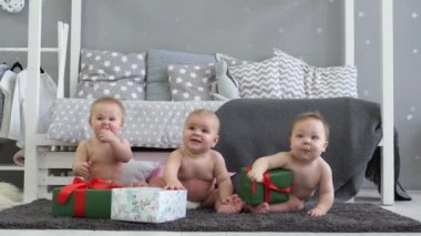 Üç bebek gülümsüyor evde çocuk odasında. Hediyeler