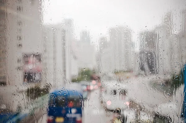 Verschwommene Regentropfen auf der Busscheibe, städtische Ansicht von Regentropfen fallen — Stockfoto