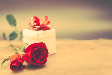 Sevgililer günü hediye kutusu ve kırmızı gül ahşap tablo rustik tarzı üzerinde arka plan