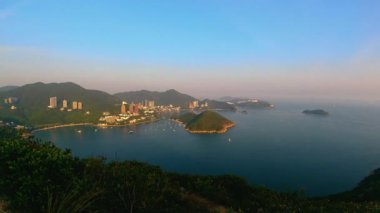 Bulutların, teknelerin, Orta adaların, derin su körfezindeki binaların akşam çekimlerinde tuğla tepe (nam long shan)