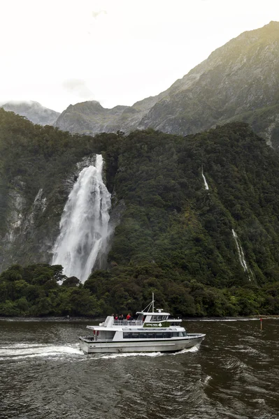 Milford Sound, Nova Zelândia - fevereiro 2016 - Navio de cruzeiro turístico passando por Lady Bowen Falls, Milford Sound, Nova Zelândia — Fotografia de Stock