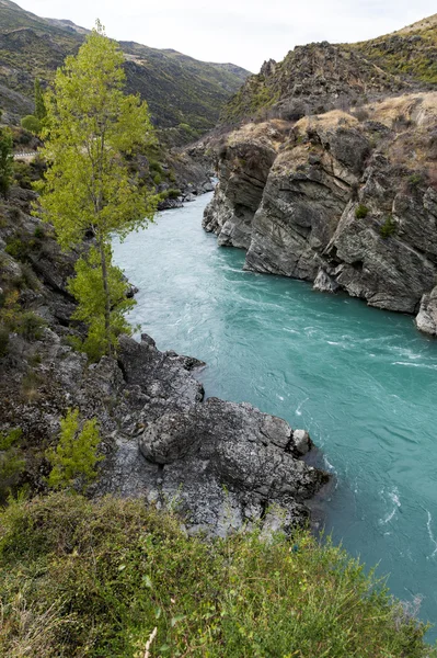 The Roaring Meg (Te Wai sebuah Korokio) aliran bergolak yang keduanya menggerakkan pembangkit listrik tenaga air ini dan bergabung dengan Sungai Kawarau, Otago Tengah, pulau selatan Selandia Baru — Stok Foto