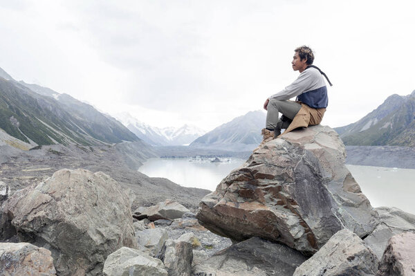 A man at Tasman Glacier viewpoint where New Zealand's longest glacier begins and the lower reaches where the ice meets the terminal lake, Aoraki / Mount Cook National Park