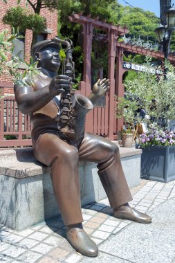 Kobe, Japonya - Nisan 2016: Kobe, Japonya Kitano bölgesinin tarihi alanında fırıldak evin önünde trompetçi heykeli