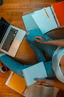 Bir kız yerde oturuyor, dizüstü bilgisayarda çalışıyor ve çay içiyor..