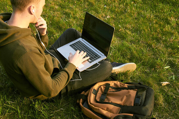young man working in laptop sitting on grass