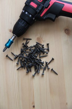 İnşaat aletleri tornavida ve vidalar ahşap bir masanın üzerinde yatıyor.