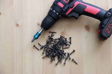 İnşaat aletleri tornavida ve vidalar ahşap bir masanın üzerinde yatıyor.