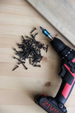 İnşaat aletleri tornavida ve vidalar ahşap bir masanın üzerinde yatıyor.