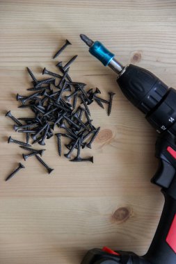 İnşaat aletleri tornavida ve vidalar ahşap bir masanın üzerinde yatıyor.
