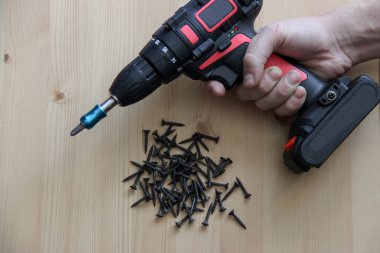 Tornavida ve vidalar. İnşaat aletleri tornavida ve vidalar ahşap bir masanın üzerinde yatıyor.