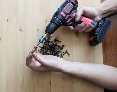 Tornavida ve vidalar. İnşaat aletleri tornavida ve vidalar ahşap bir masanın üzerinde yatıyor.