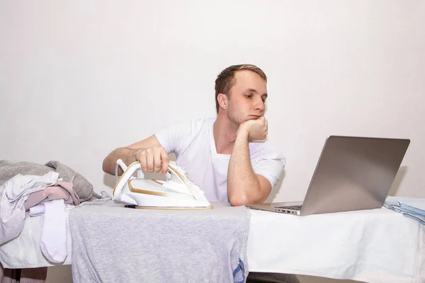a young guy at home on self-isolation works remotely and is engaged in ironing.
